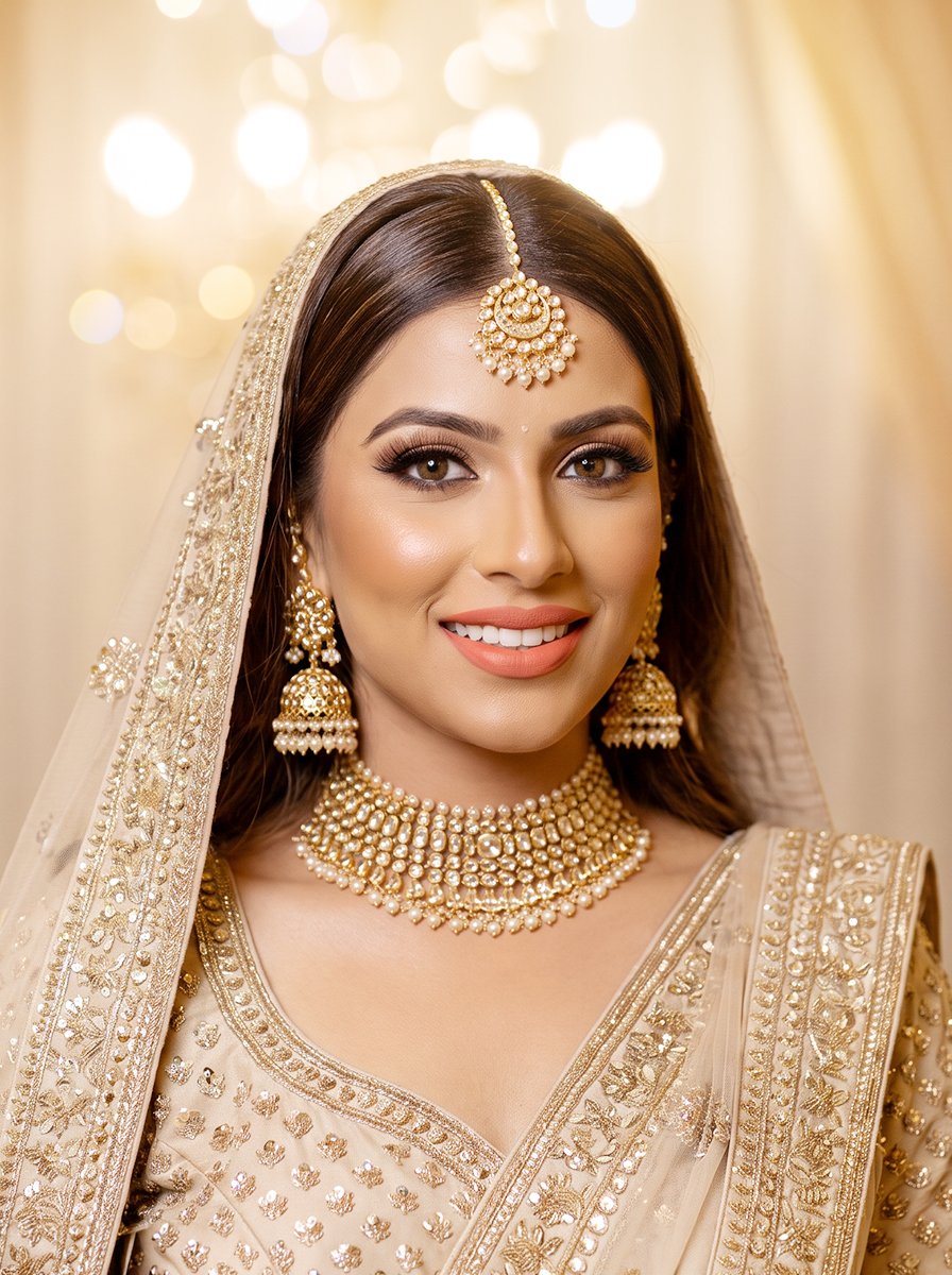 Bride wearing luminous makeup, pearl and gold jewellery, and an embroidered veil